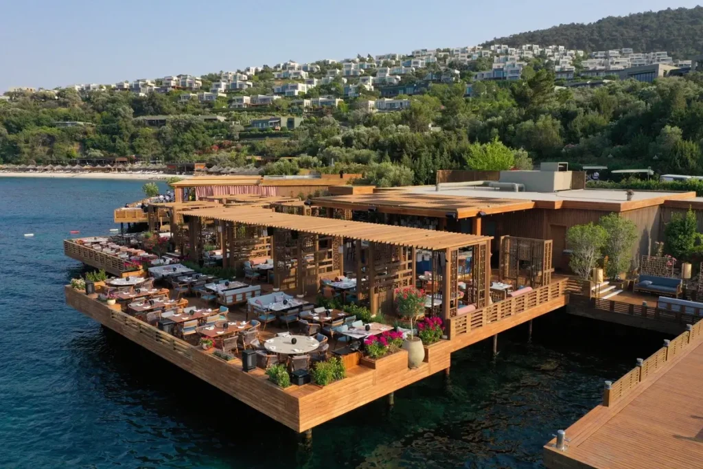Hakkasan’s open-air dining terraces extending over the water, with the resort hillside behind.