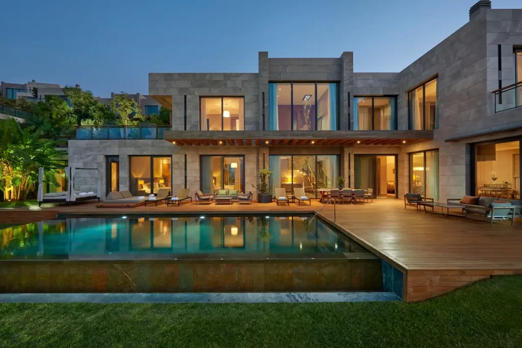 Illuminated two-story Paradise Bay Villa with a private pool, terrace, and lawn at dusk.