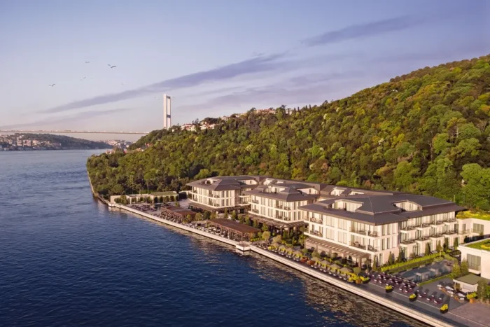 Mandarin Oriental Bosphorus, Istanbul stretches along the shoreline below a wooded hillside, with the strait and a distant bridge beyond.