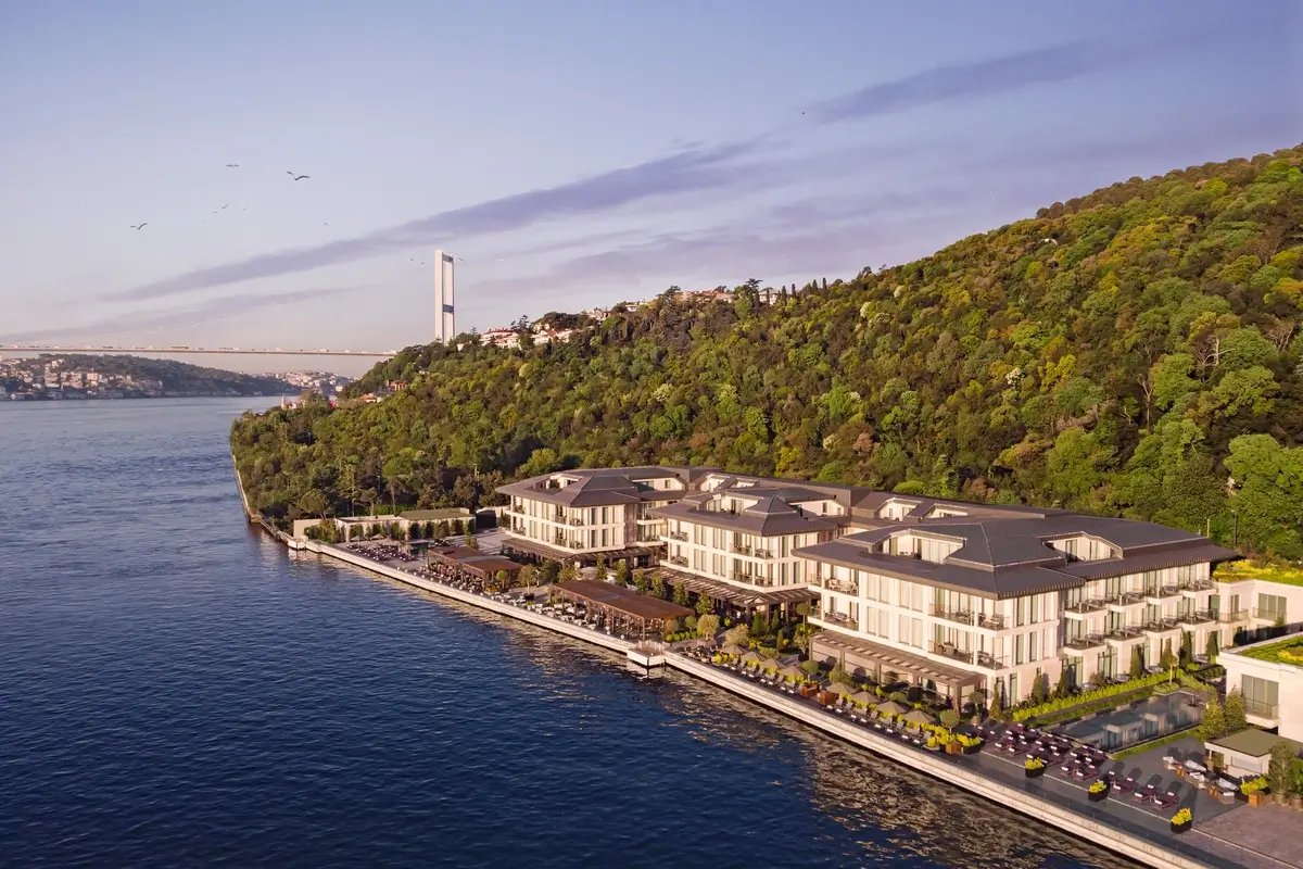 Mandarin Oriental Bosphorus, Istanbul stretches along the shoreline below a wooded hillside, with the strait and a distant bridge beyond.
