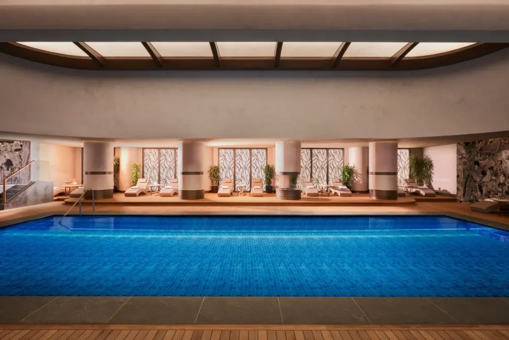 Blue indoor swimming pool with loungers and warm lighting at Mandarin Oriental Bosphorus, Istanbul.