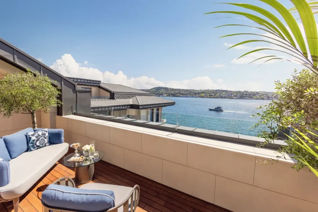 Sofa, chair, and planted borders on a Junior Bosphorus Suite terrace overlooking the strait at Mandarin Oriental Bosphorus, Istanbul.