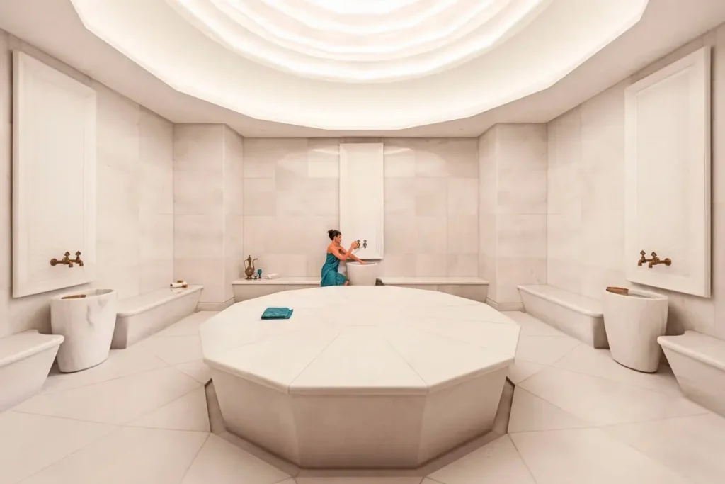 Pale marble treatment platform, wall basins, and a circular ceiling in the Turkish hammam at Mandarin Oriental Bosphorus, Istanbul.