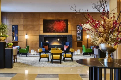 Seating arranged around a fireplace, with floral displays and artwork, in the lobby at Mandarin Oriental, Boston.