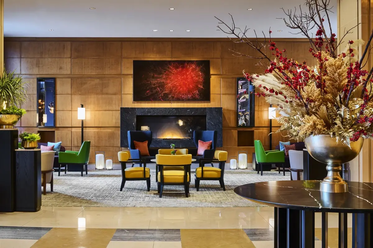Seating arranged around a fireplace, with floral displays and artwork, in the lobby at Mandarin Oriental, Boston.
