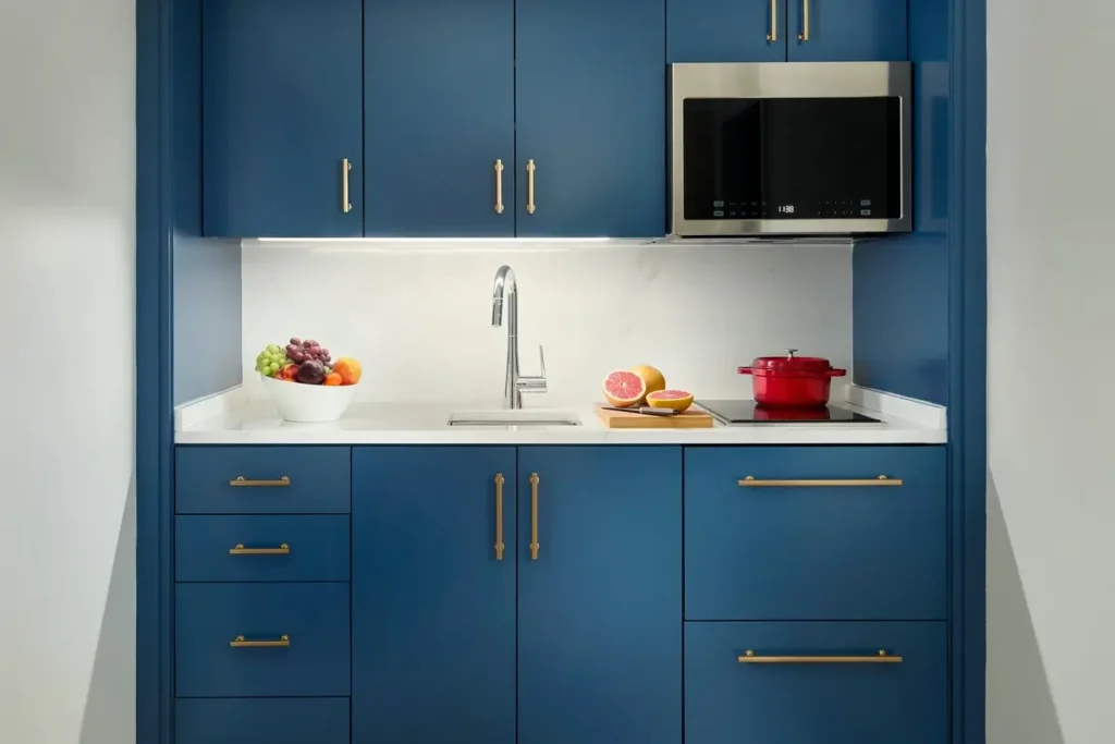 Blue cabinetry, a sink, microwave, and cooktop in the Residential Suite kitchenette at Mandarin Oriental, Boston.