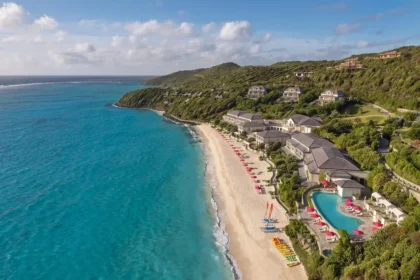 Aerial view of Mandarin Oriental, Canouan beside Godahl Beach, with the resort pool, hillside villas, and blue ocean.
