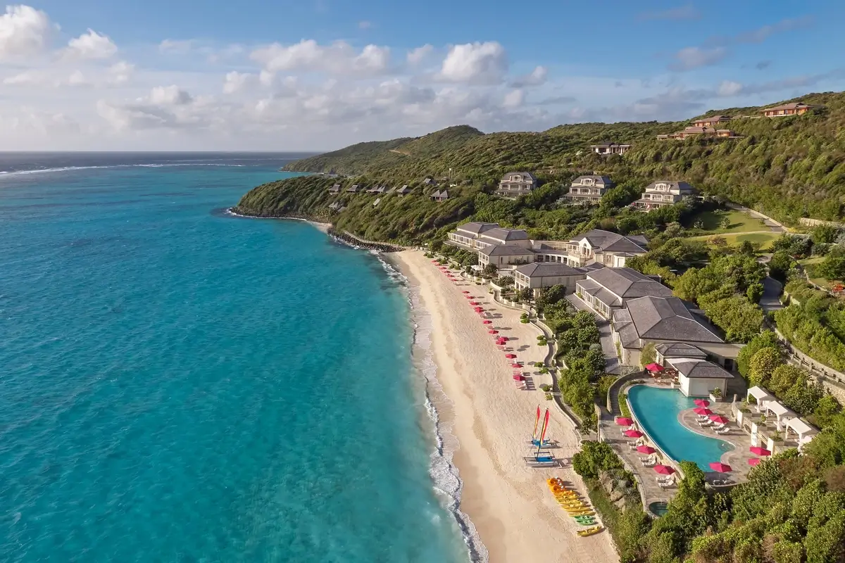 Aerial view of Mandarin Oriental, Canouan beside Godahl Beach, with the resort pool, hillside villas, and blue ocean.