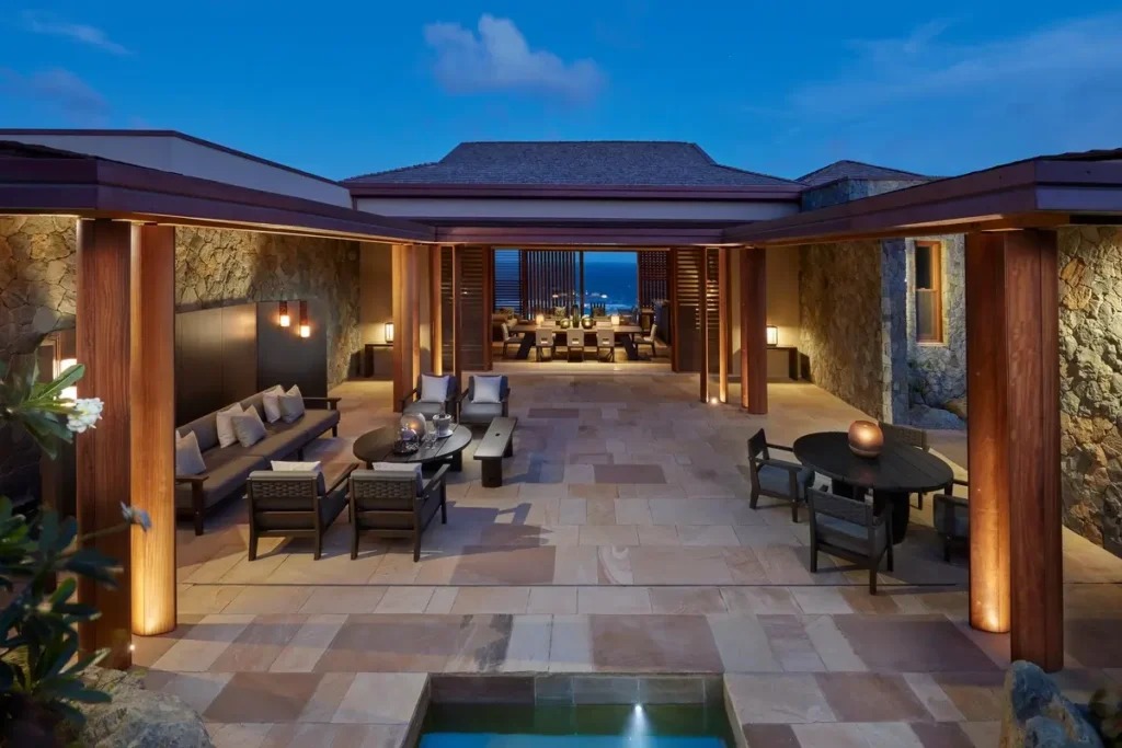 Outdoor sofas and chairs around a stone terrace with a small water feature at a Patio Villa at Mandarin Oriental, Canouan.