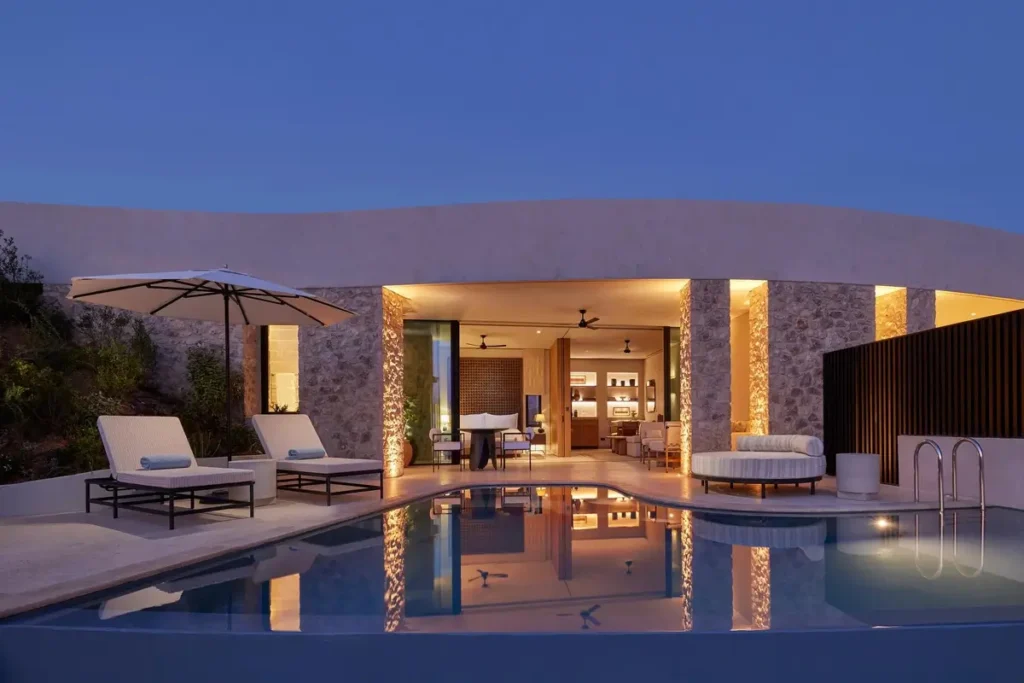 Private pool and loungers outside an illuminated Mandarin Pool Villa at dusk.