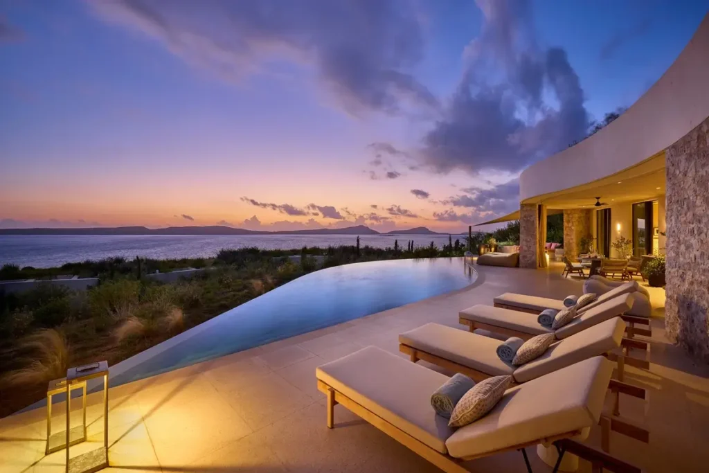 Pool and loungers on a Three Bedroom Villa terrace overlooking the bay at sunset.