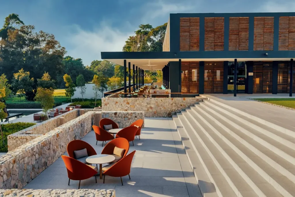 Red chairs beside broad steps leading toward the timber-screened resort lobby at Mandarin Oriental, Desaru Coast.