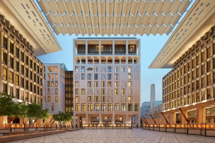 Mandarin Oriental, Doha overlooking a paved square framed by pale stone buildings and an overhead shade structure.