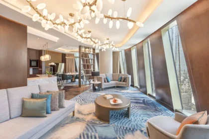 Curved sofas, a dining area, sculptural lights, and tall sloping windows in the Mandarin Signature Suite.