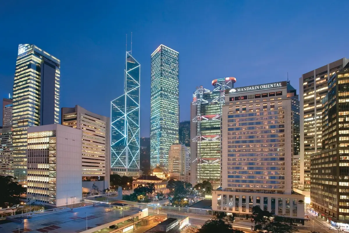 Mandarin Oriental, Hong Kong illuminated beside the towers of Central at dusk.