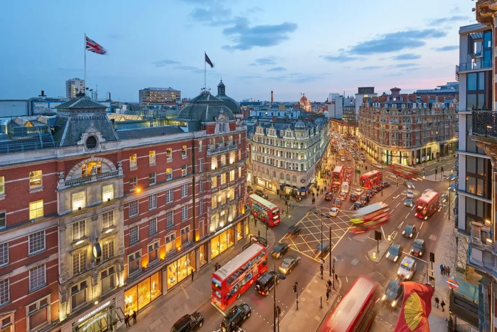 Elevated view of Knightsbridge shops, buses, and surrounding buildings at dusk.