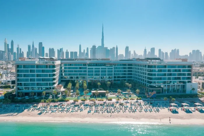 Mandarin Oriental Jumeira facing a sandy beach and the Arabian Gulf, with Dubai’s skyline rising behind the hotel.