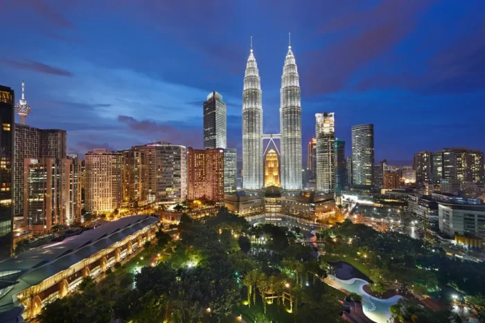 Petronas Twin Towers and surrounding buildings above the landscaped park at dusk.