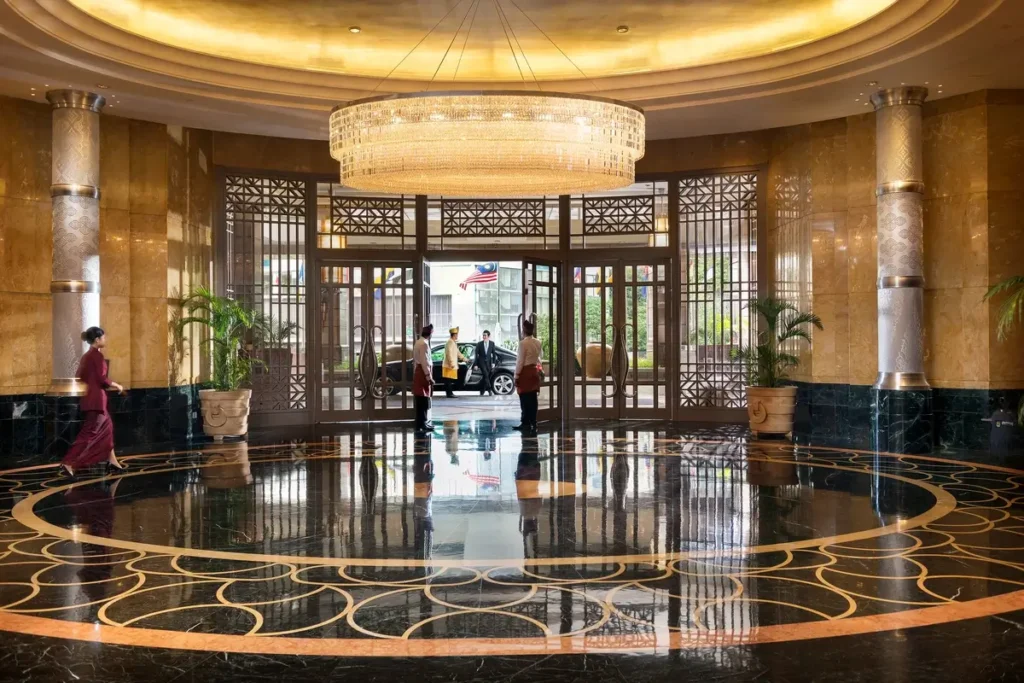 Circular patterned marble floor, large chandelier, and glass entrance doors in the hotel lobby.