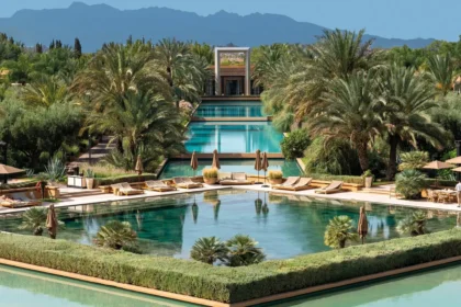 Landscaped water features, palms, and low-rise buildings with mountains beyond at Mandarin Oriental, Marrakech.