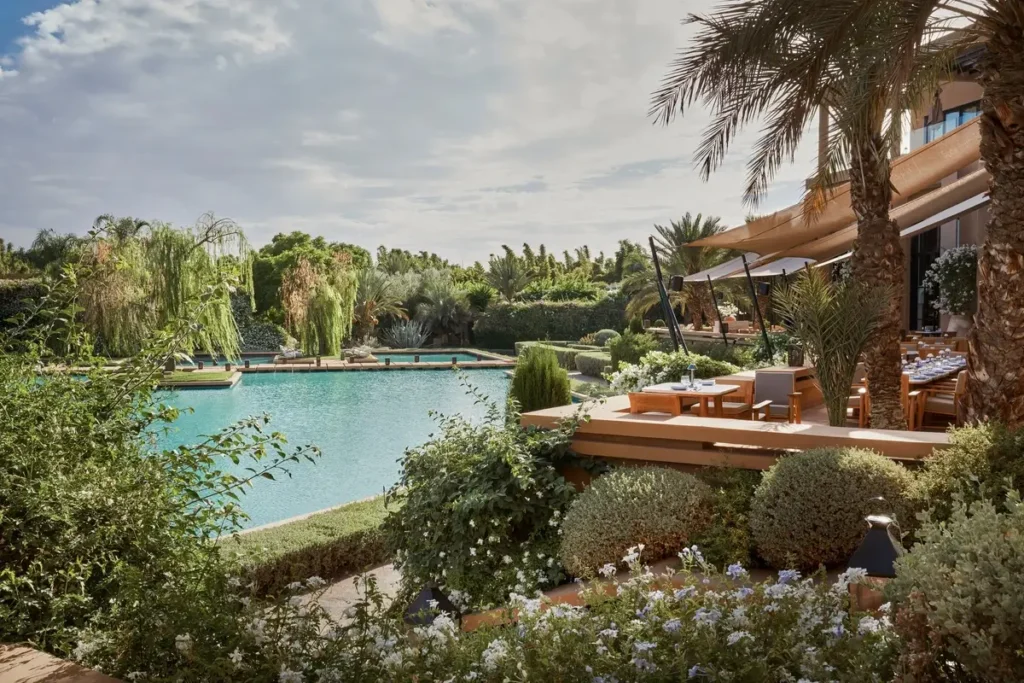 Trees, shrubs, water, and shaded outdoor seating in the landscaped grounds of Mandarin Oriental, Marrakech.