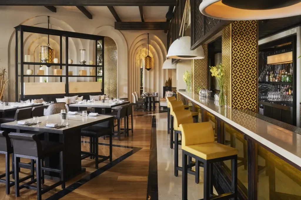 Dining tables and a long bar with yellow stools inside Ling Ling at Mandarin Oriental, Marrakech.