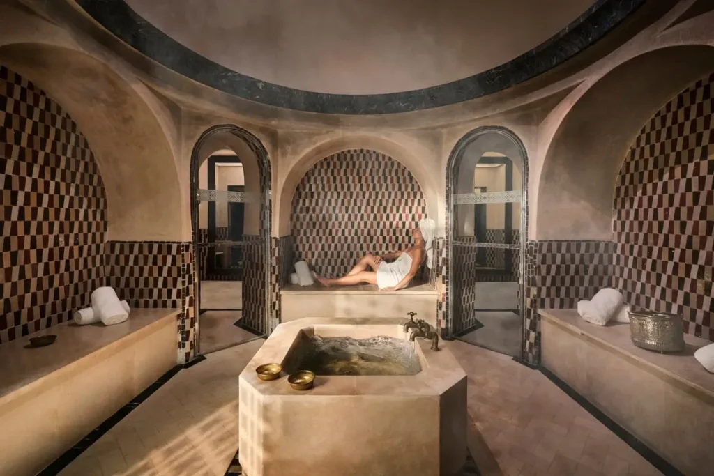 Stone treatment tables beneath curved ceilings and patterned wall recesses in the spa hammam.