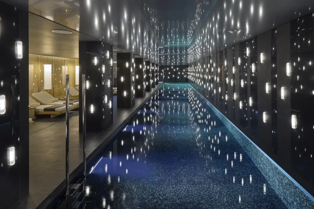 Long indoor swimming pool beneath a dark ceiling, with points of light reflected across the water.