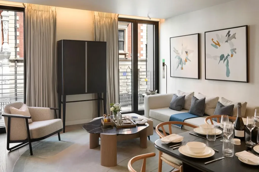 Sofa, armchairs, coffee table, dining table, and tall windows in a three-bedroom apartment.