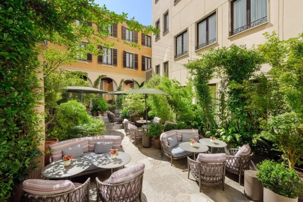 Round tables, woven chairs, cushioned seating, and dense planting in Mandarin Garden’s courtyard.