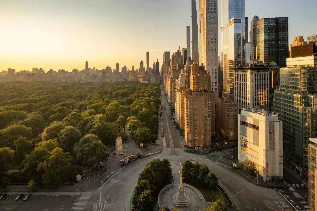 Elevated view across Columbus Circle, Central Park, and Manhattan towers in warm evening light.