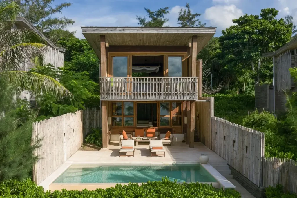 A two-story timber villa has an upper balcony, a shaded lower terrace, and a rectangular private pool.