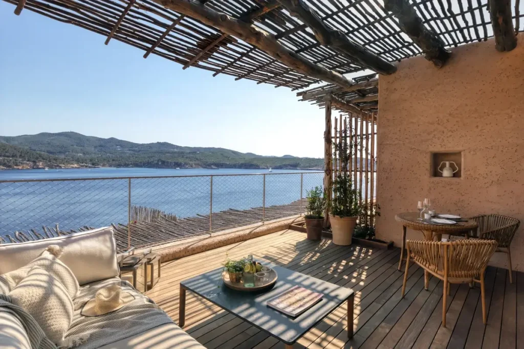 Shaded timber terrace with cushioned seating and a sea view at a Sea View Junior Suite at Six Senses Ibiza