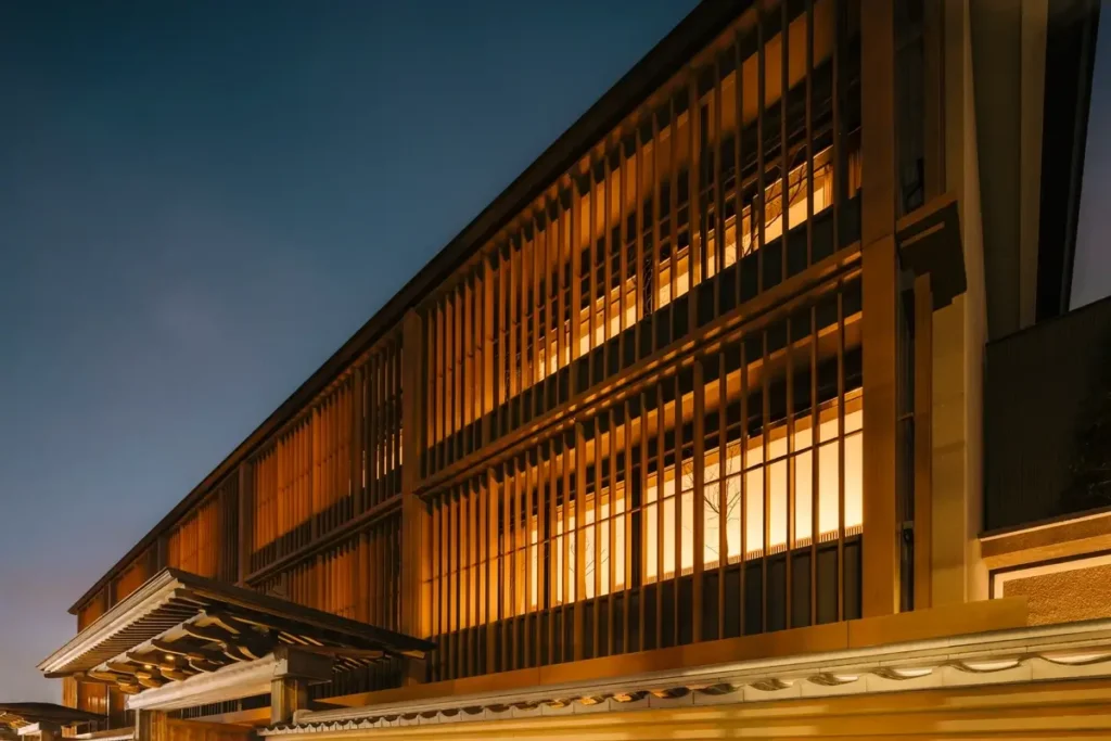 Illuminated windows behind vertical facade screens at Six Senses Kyoto at dusk