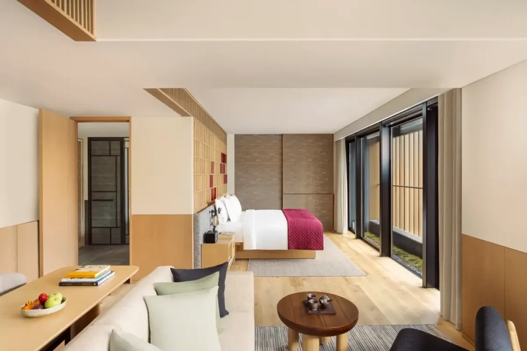 Light-filled suite with a sofa, low tables, timber flooring, and a separate sleeping area at Six Senses Kyoto