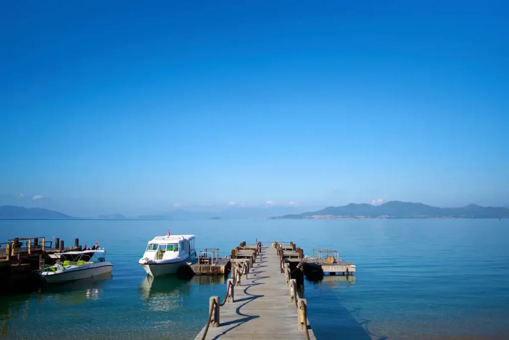 Wooden jetty extending into calm blue water beside moored boats at Six Senses Ninh Van Bay