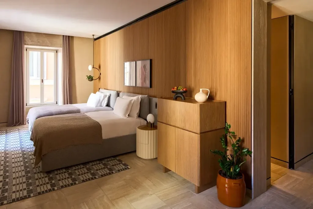 Twin beds, warm wood paneling, and patterned flooring in a Deluxe Junior Suite at Six Senses Rome