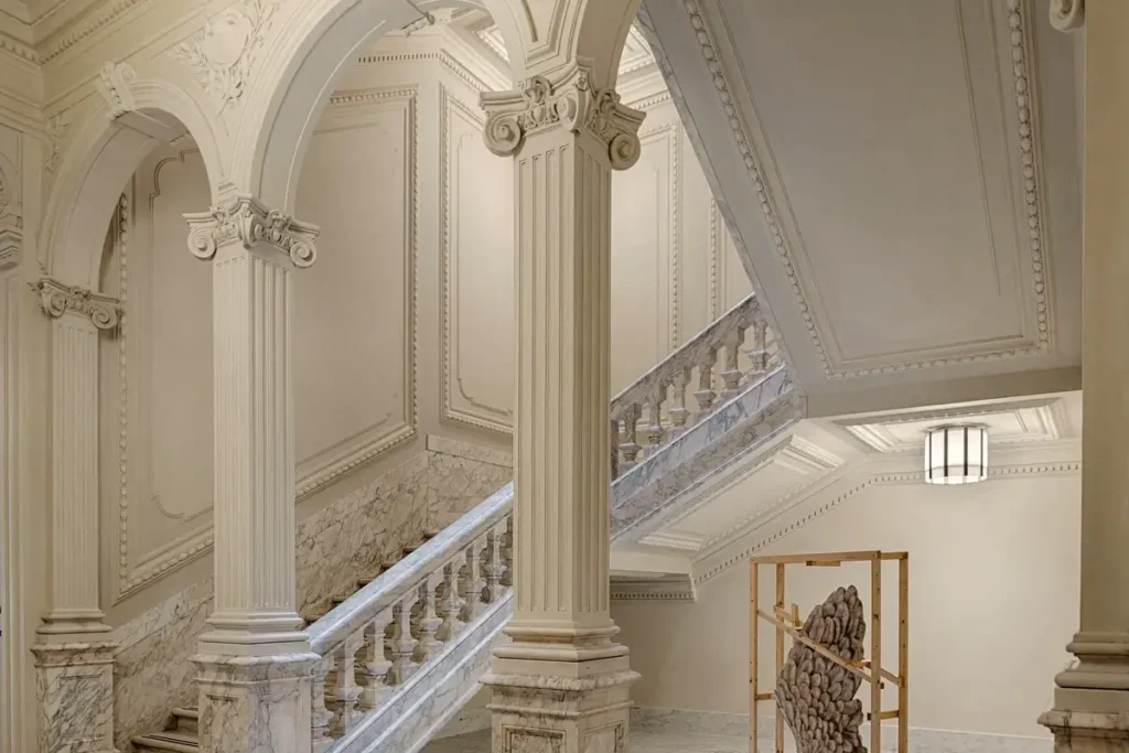 Marble staircase with carved balustrades, decorative columns, and arched ceilings at Six Senses Rome