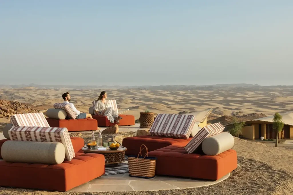 Orange lounge seating and low tables on the Al Sarab terrace overlooking desert dunes