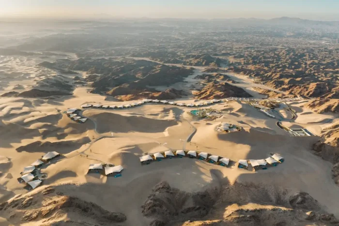 Aerial view of resort buildings arranged among sweeping dunes at Six Senses Southern Dunes