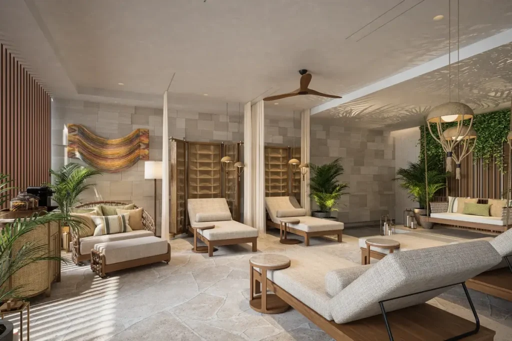 Pale recliners and cushioned daybeds stand among plants, stone walls, and slender columns in a bright spa lounge.